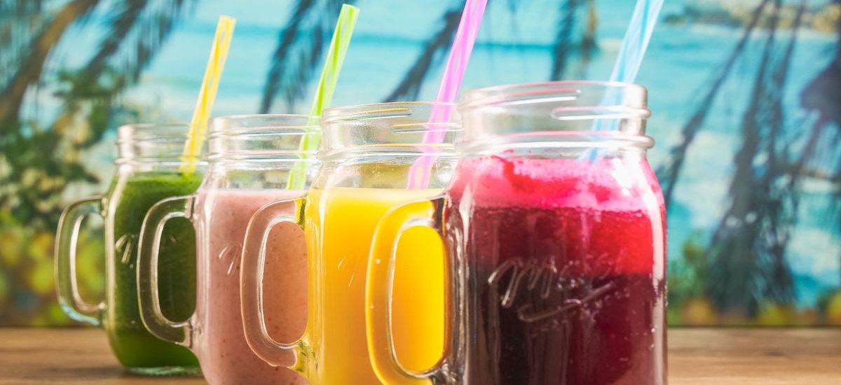 Vibrant fruit juices in mason jars with colorful straws, perfect for a summer refreshment.