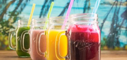 Vibrant fruit juices in mason jars with colorful straws, perfect for a summer refreshment.