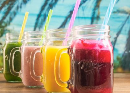 Vibrant fruit juices in mason jars with colorful straws, perfect for a summer refreshment.