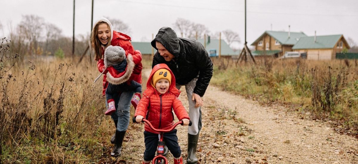 Happy family enjoying a rainy day outside with a bike ride and playful togetherness.