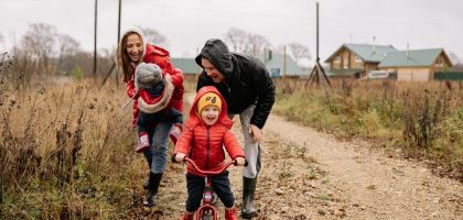 Happy family enjoying a rainy day outside with a bike ride and playful togetherness.