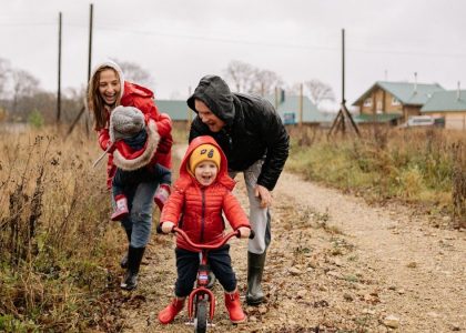 Happy family enjoying a rainy day outside with a bike ride and playful togetherness.