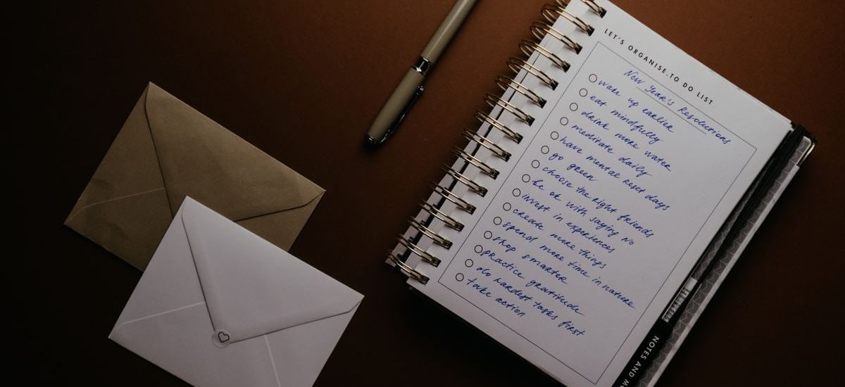 Flat lay of a to-do list, pen, and envelopes on a brown surface, ideal for planning themes.