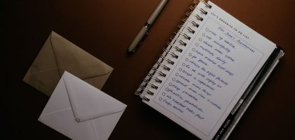 Flat lay of a to-do list, pen, and envelopes on a brown surface, ideal for planning themes.