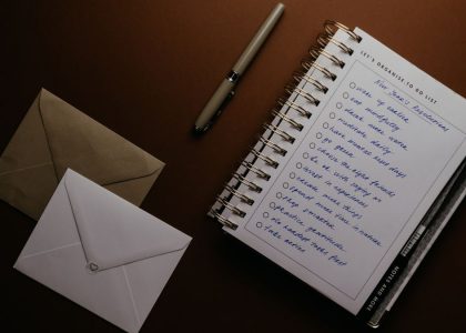 Flat lay of a to-do list, pen, and envelopes on a brown surface, ideal for planning themes.